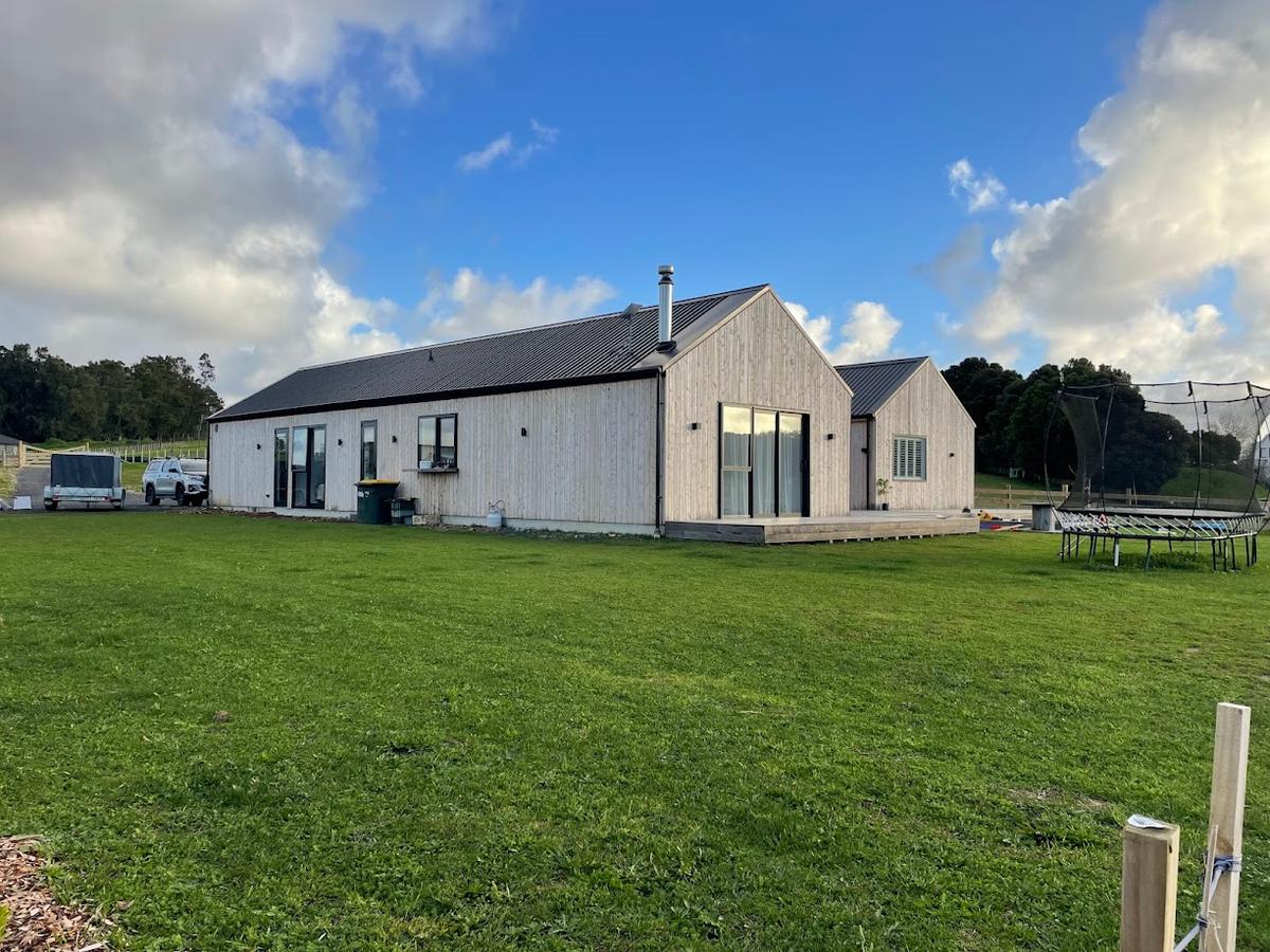 The pavilion seen across the lawn, under a dark standing seam roof