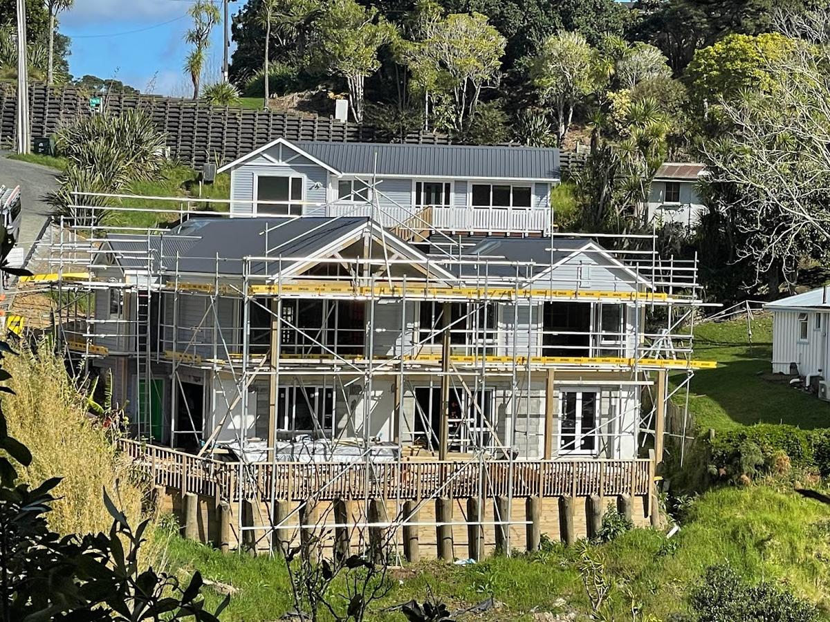 Scaffolded house sitting above a new timber pole retaining wall