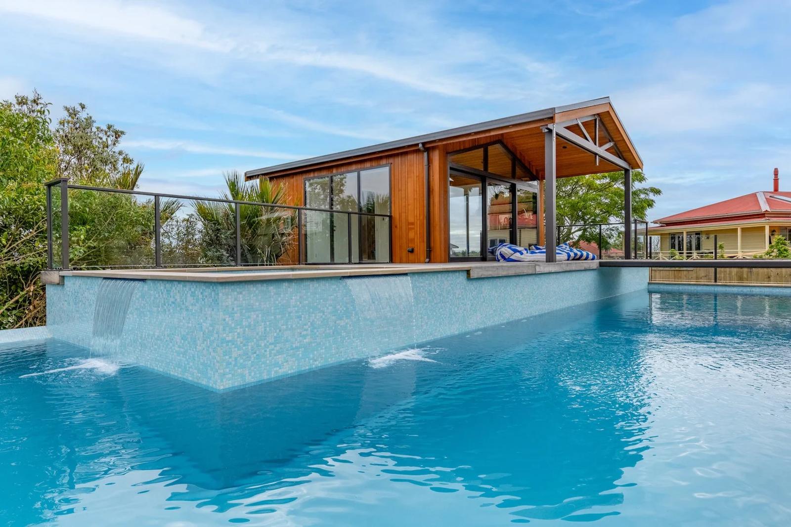 Poolside pavilion with a timber gable, seen across the pool