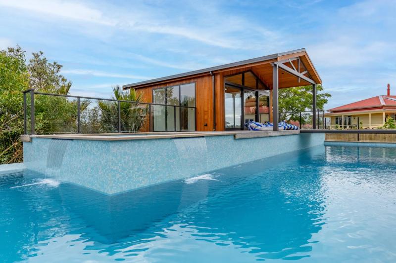 Poolside pavilion with a timber gable, seen across the pool