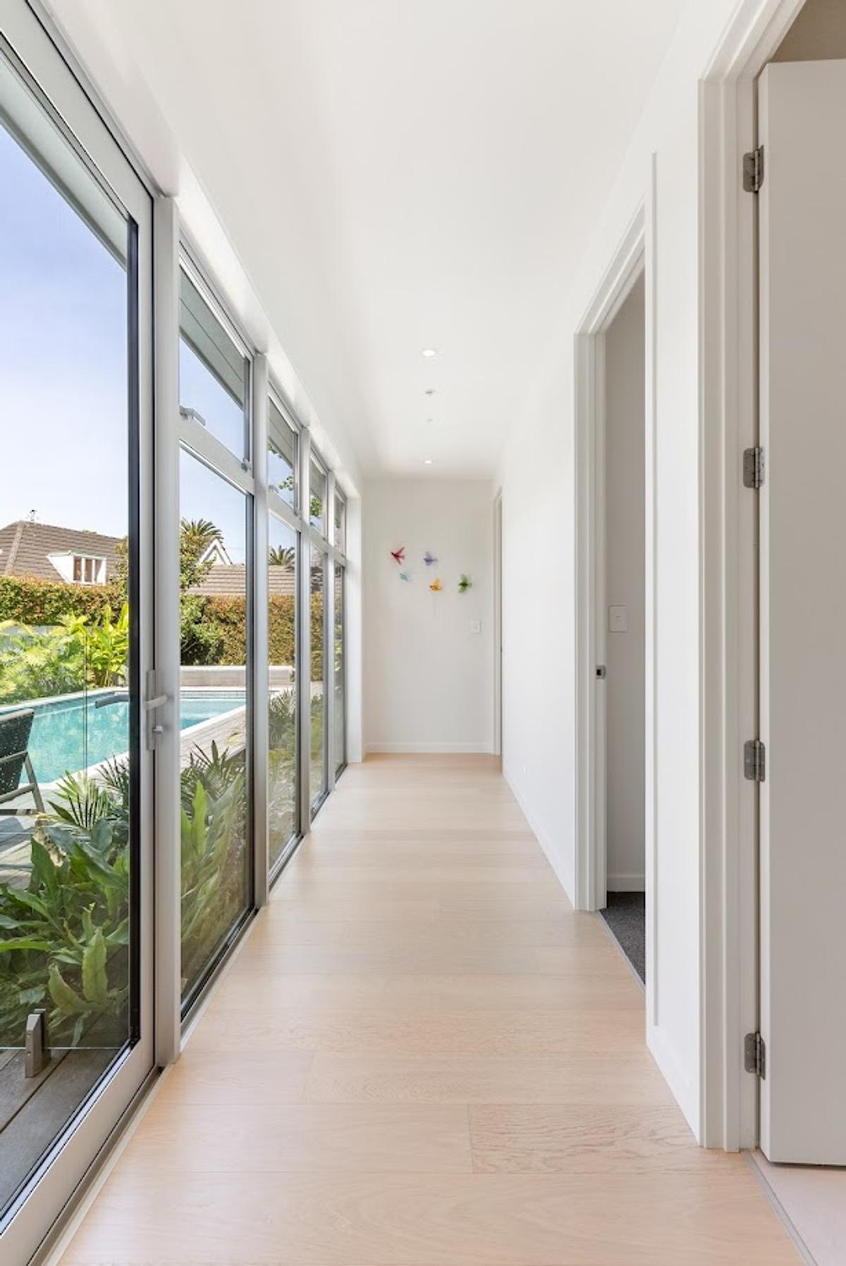 Hallway glazed from floor to ceiling along one side, looking out to the pool