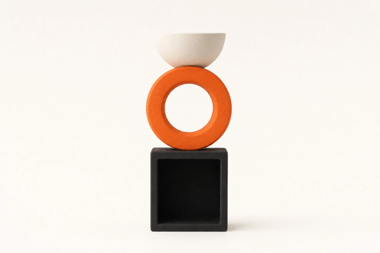 A vertical totem of three hollow matte ceramic forms stacked dead-on against a bone cream backdrop: a low open black cube at the bottom showing a square dark interior, a tangerine ring in the middle with its circular opening facing the camera, and a small ivory half-bowl at the top opening upward.