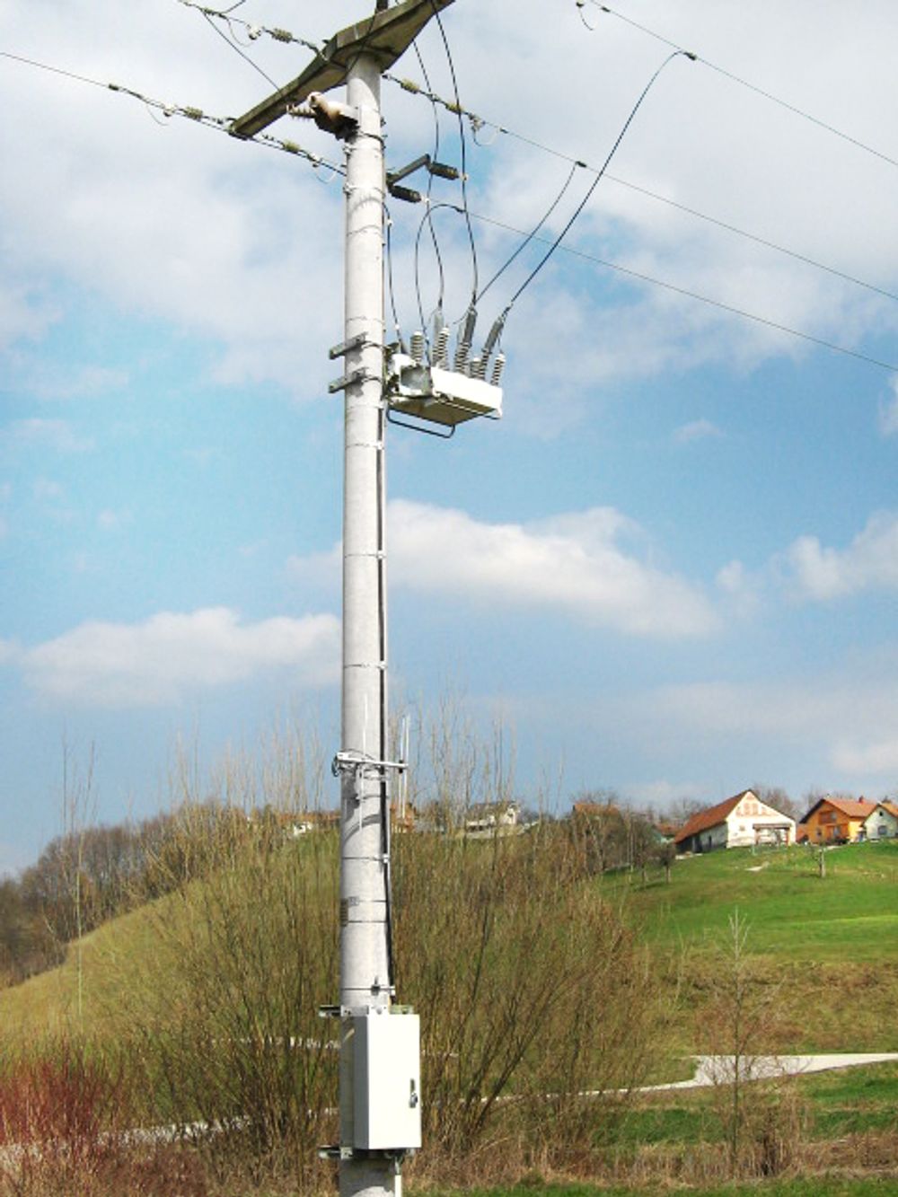 NOJA Power OSM Recloser Installation on a hill with red and white houses in the background 