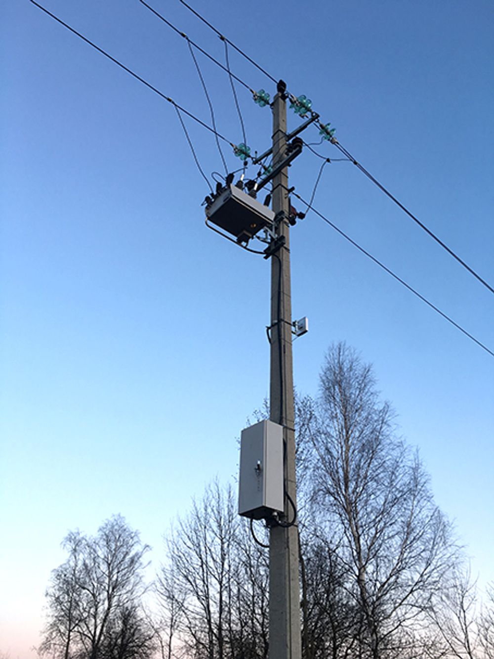 NOJA Power OSM Recloser Installation with light blue skies and tree tops in the background