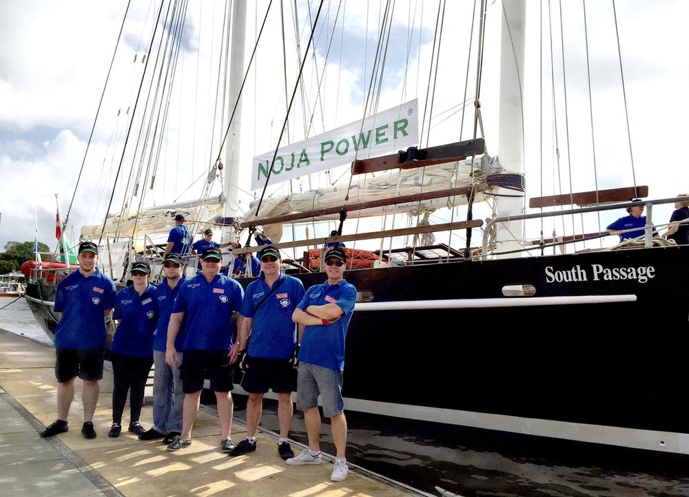 NOJA Power Directors Neil O’Sullivan, Oleg Samarski, Jay Manne (third, fourth, and fifth left) and NOJA Power Staff Sam Griffiths, Samantha Stone, Ashley Smith (first, second and third left) standing in front of 30.5-metre long tall ship 