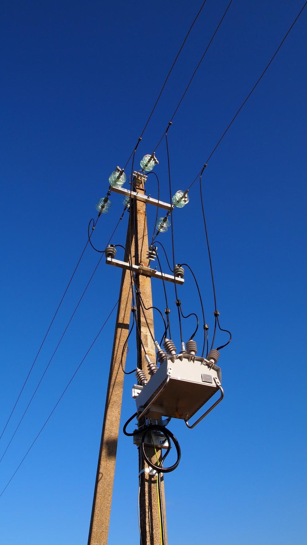 Pole mounted NOJA Power OSM38 Recloser in Lithuania taken from below with clear blue skies