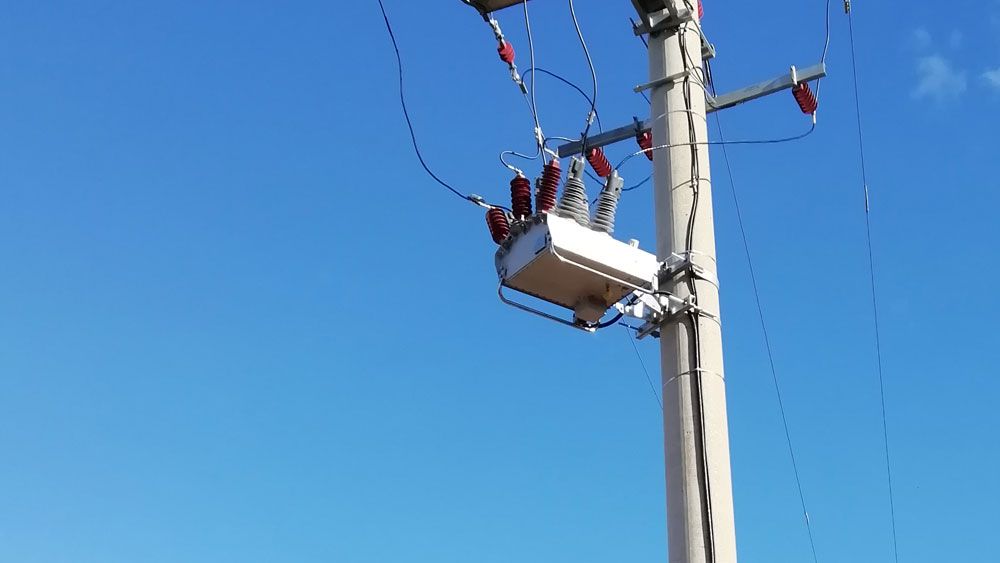 Image of pole mounted NOJA Power OSM Recloser from below, with clear blue skies behind