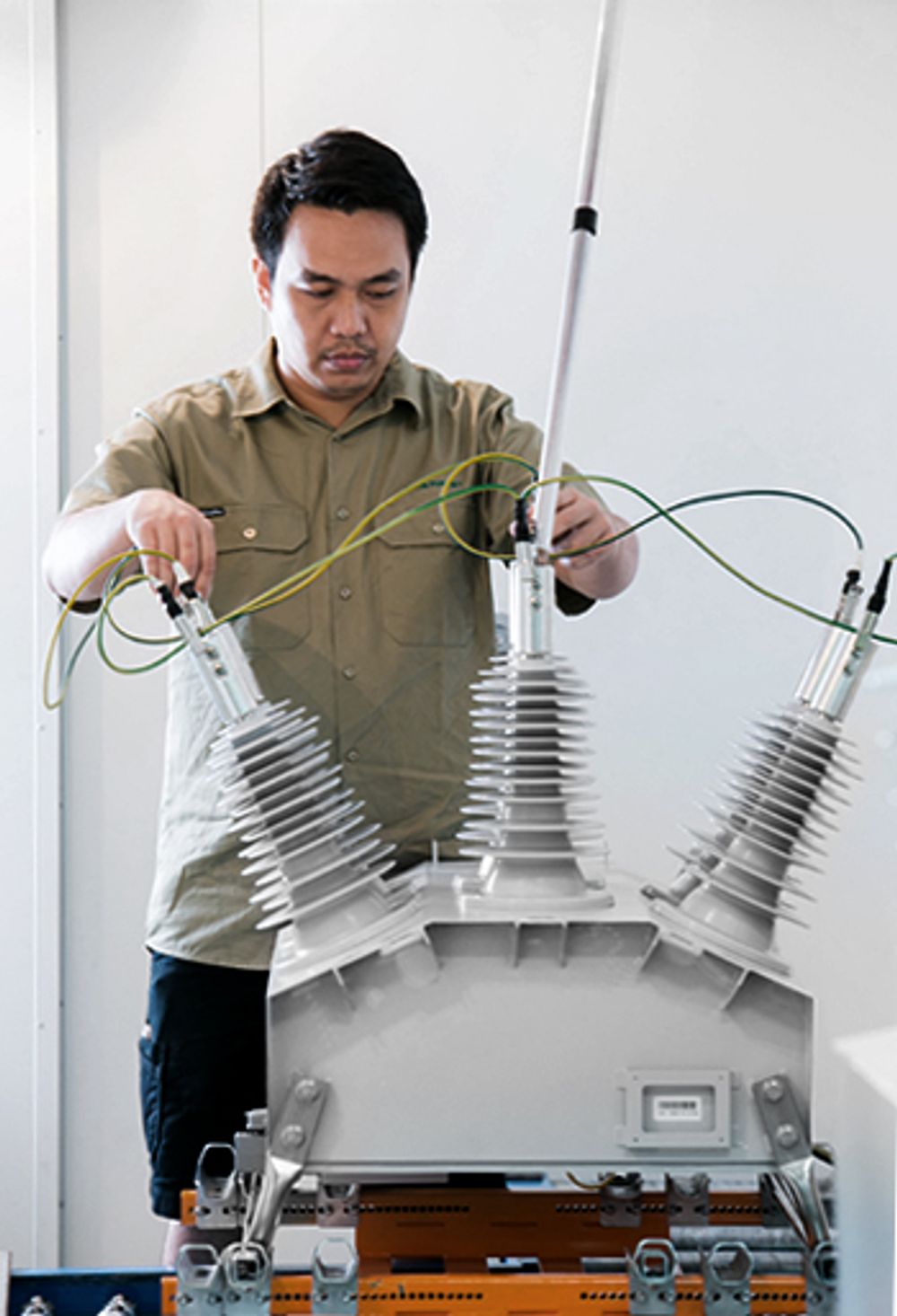 Man holding testing connectors on bushings of NOJA Power OSM Recloser under test 