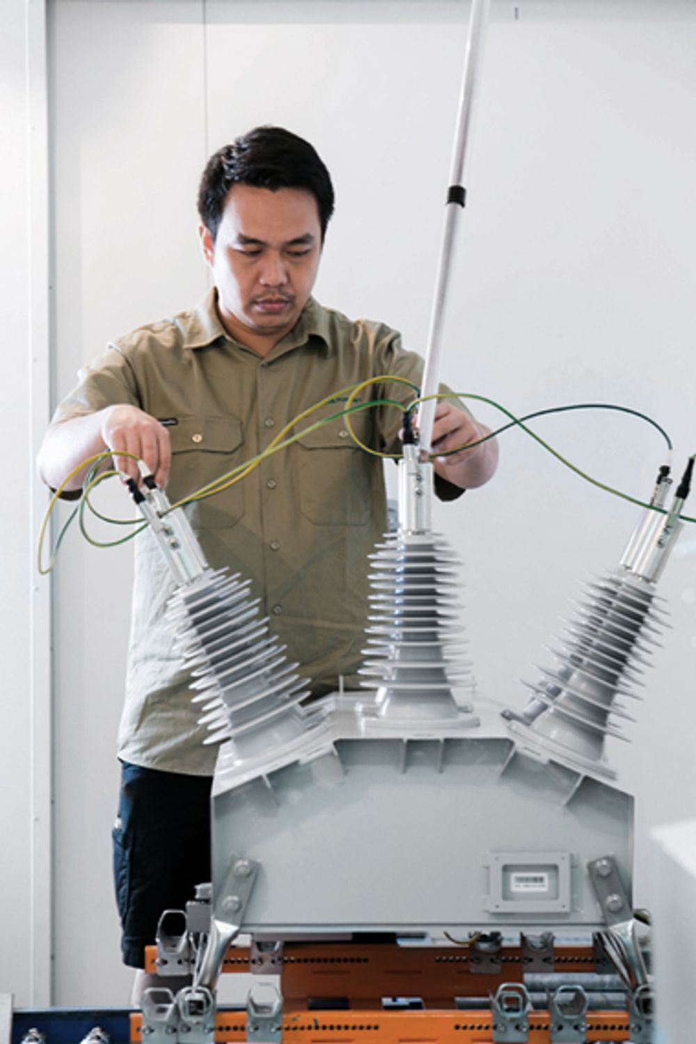 Man holding test connectors to OSM Recloser with Tunnel Connections under routine test at the NOJA Power Factory