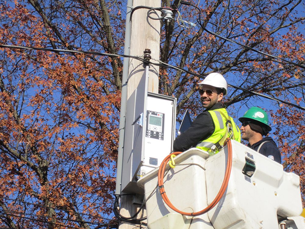 Image of two men in line bucket truck, one facing the NOJA Power RC Controller and one facing back towards the camera