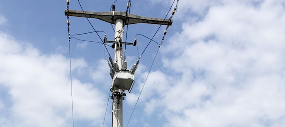 Taken from below, image of a pole mounted NOJA Power OSM Recloser with cloudy blue skies behind 