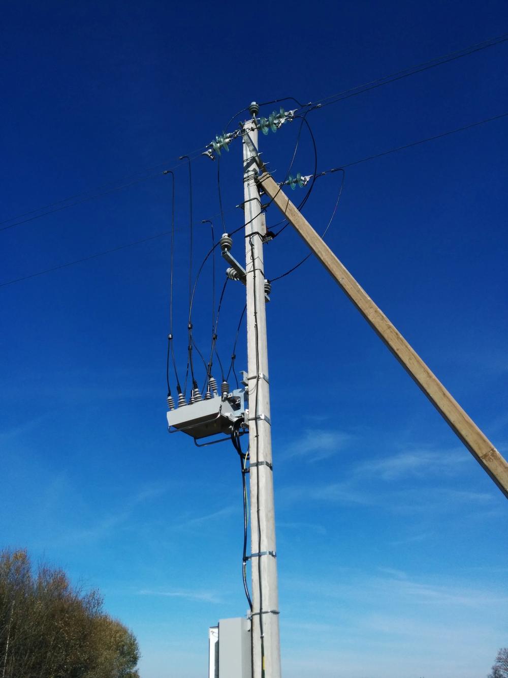 Pole mounted NOJA Power OSM Recloser in Lithuania taken from below with clear blue skies