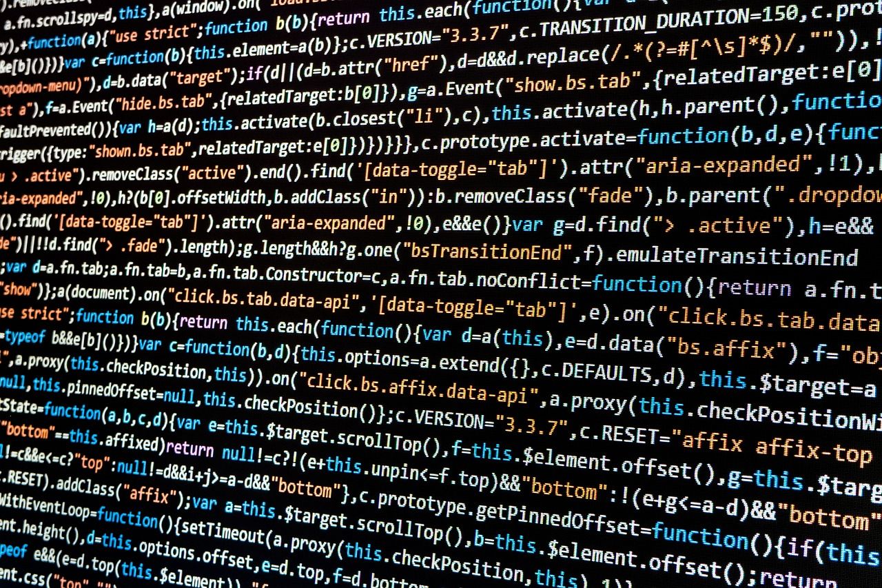 Close-up of a monitor showing colorful JavaScript code on a dark background, with syntax highlighting