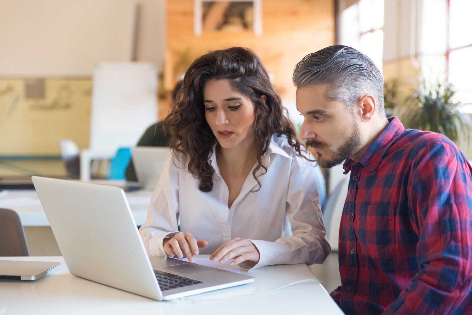Two engineers discussing pilot results on a laptop while evaluating an AI coding tool