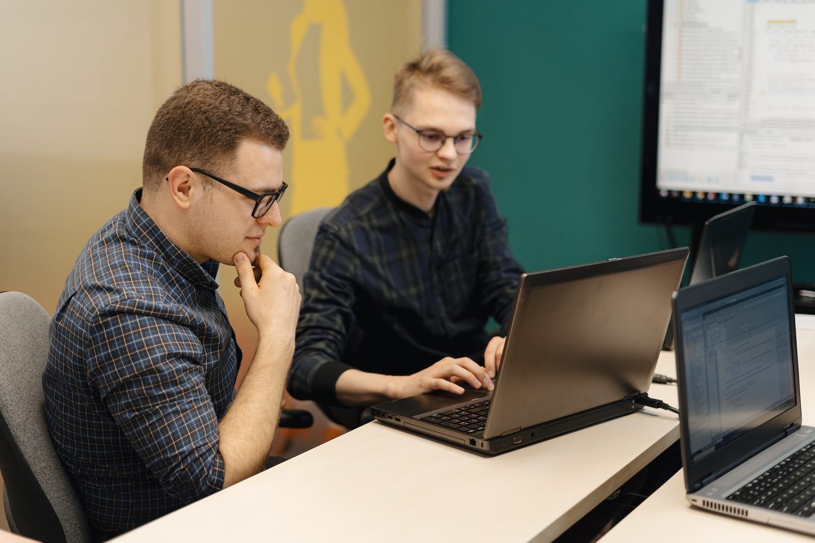 Two engineers reviewing test results together on a laptop in a meeting room