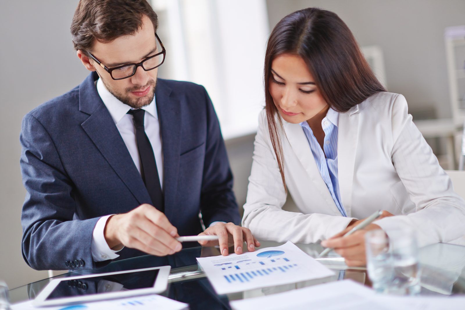 Two executives reviewing a printed budget report with charts during a planning review