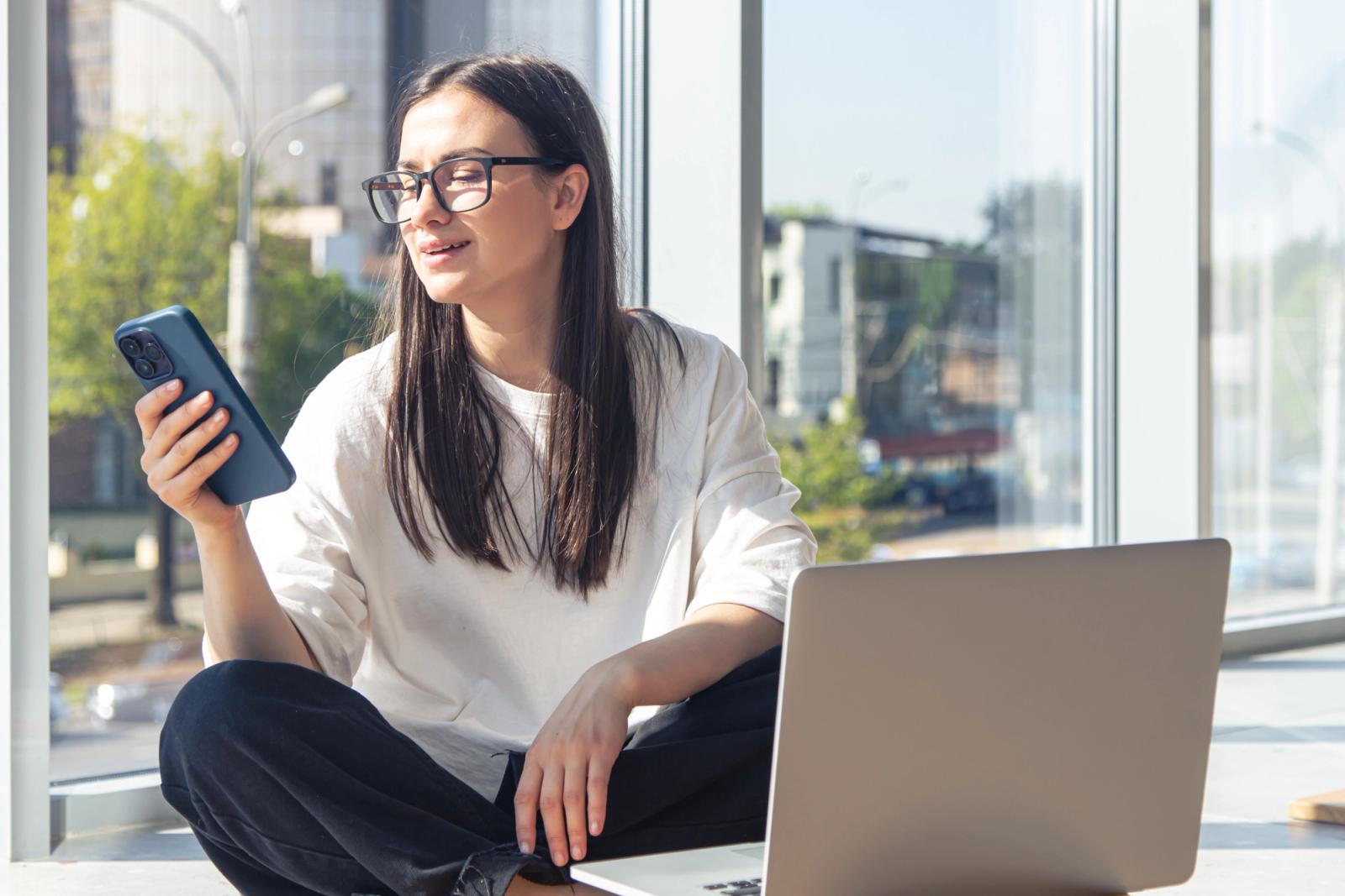 QA engineer checking a one-time passcode on a smartphone next to an open laptop running tests
