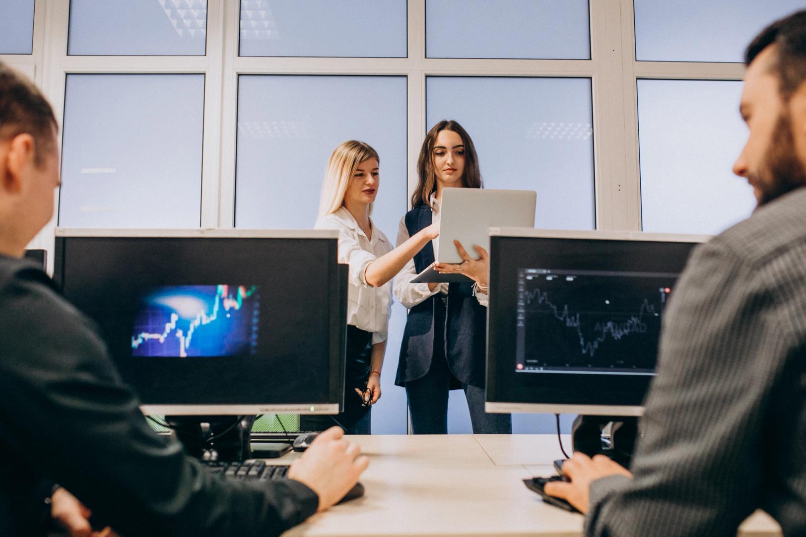 Release manager presenting a cross-system release plan while engineers watch test dashboards on their monitors