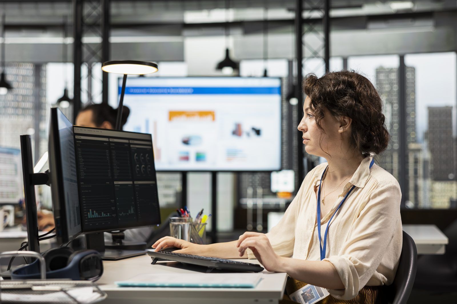 Engineering manager reviewing delivery and quality metrics on multiple monitors in an open office