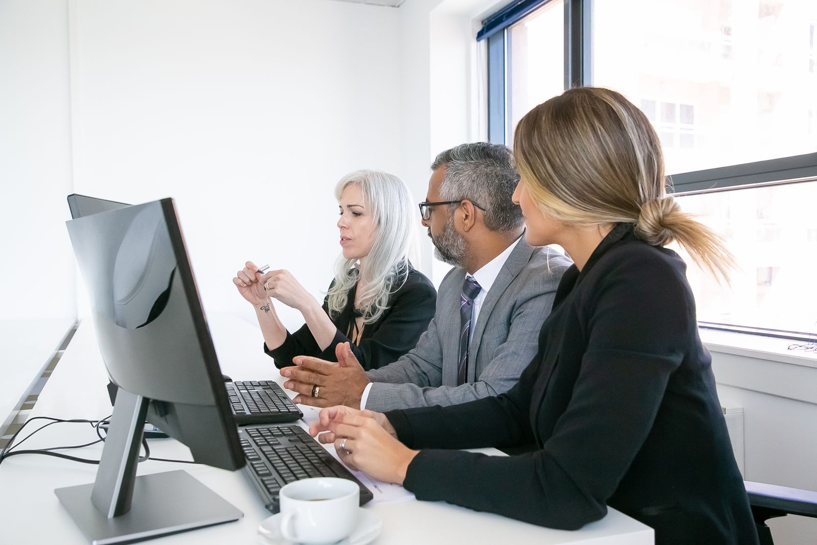 QA leads and an enterprise architect reviewing a cross-application business process test on a desktop monitor
