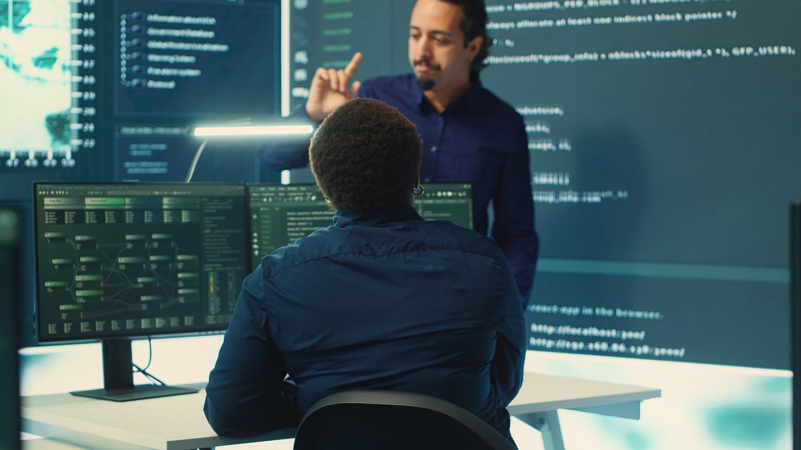 Engineers in an operations center reviewing logs on large screens to decide whether to roll back an automated change
