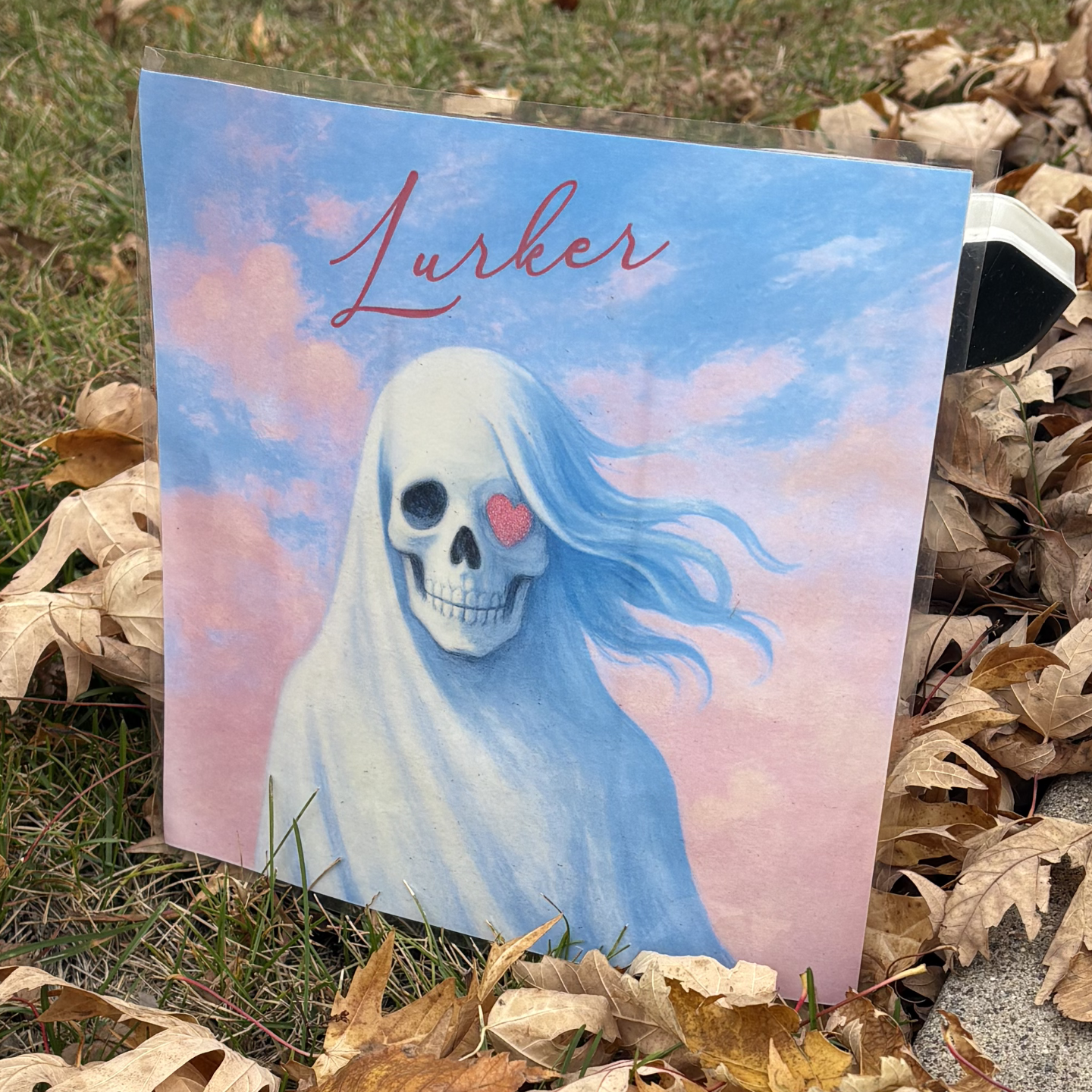 Artwork for an album that parodies Taylor Swift's album "Lover". It depicts a feminine skull with a heart instead of one eye and in script font the words "Lurker"