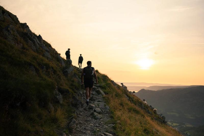 Hikers and sheep on a hillside against the Sunrise