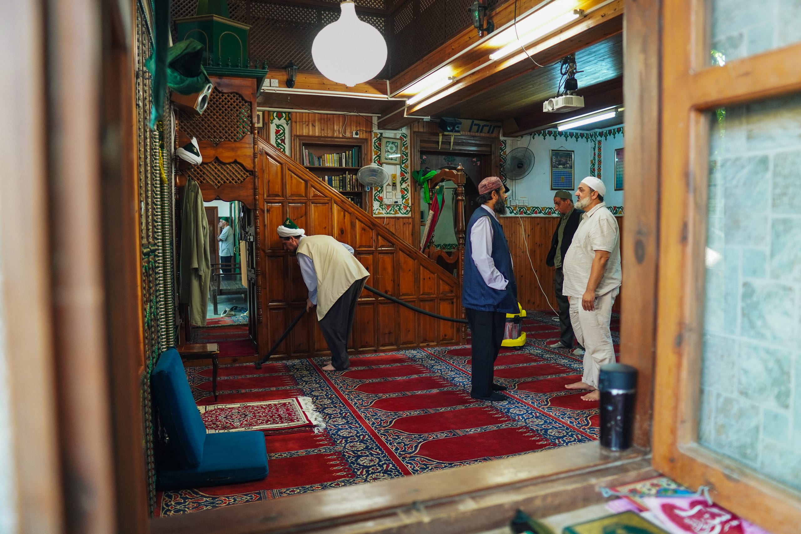 Peaking through a window, men stand in conversation inside a mosque