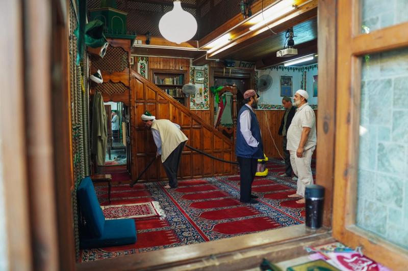 Peaking through a window, men stand in conversation inside a mosque