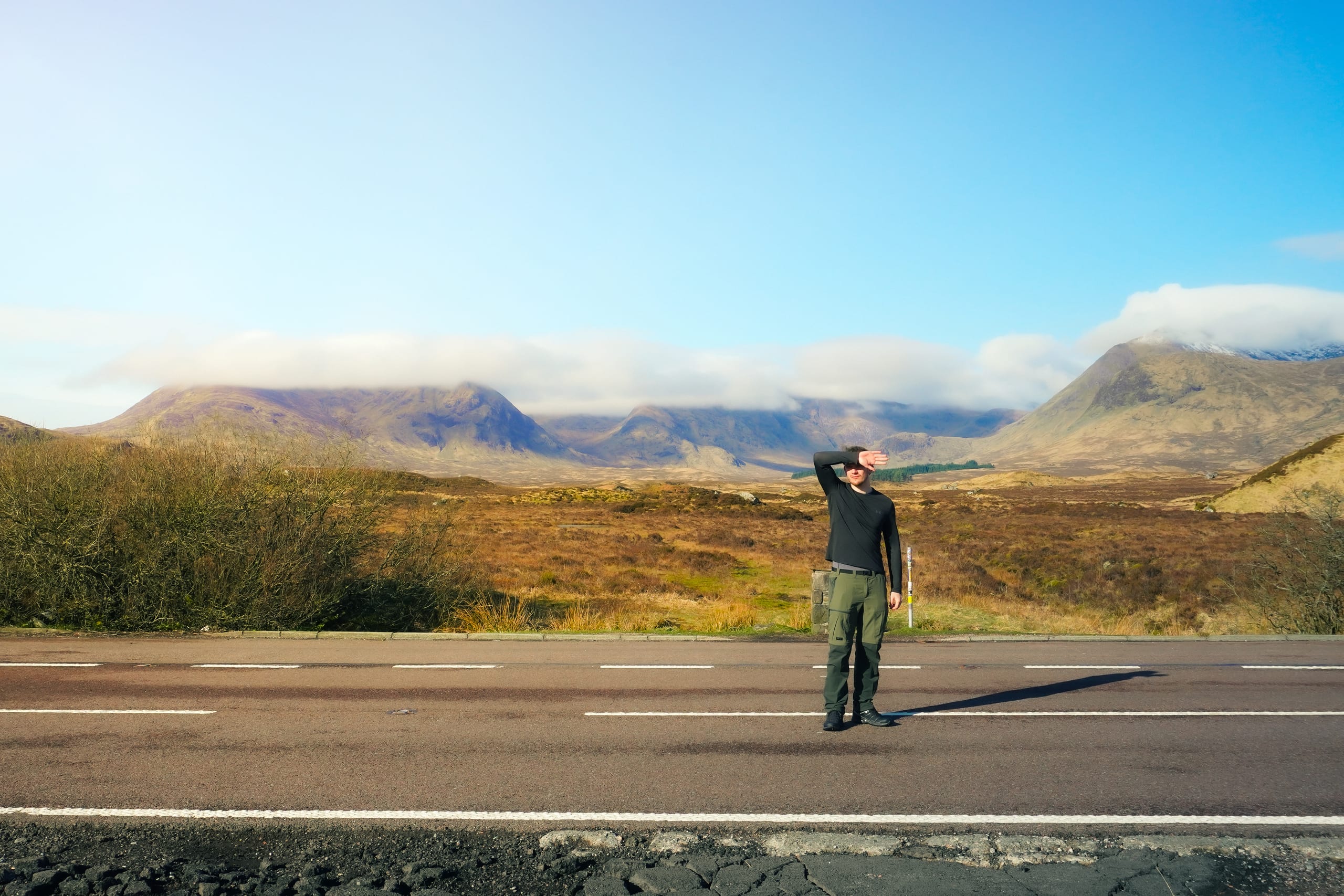 Man on a road, with a background of clouded mountains