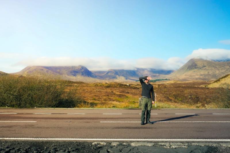 Man on a road, with a background of clouded mountains