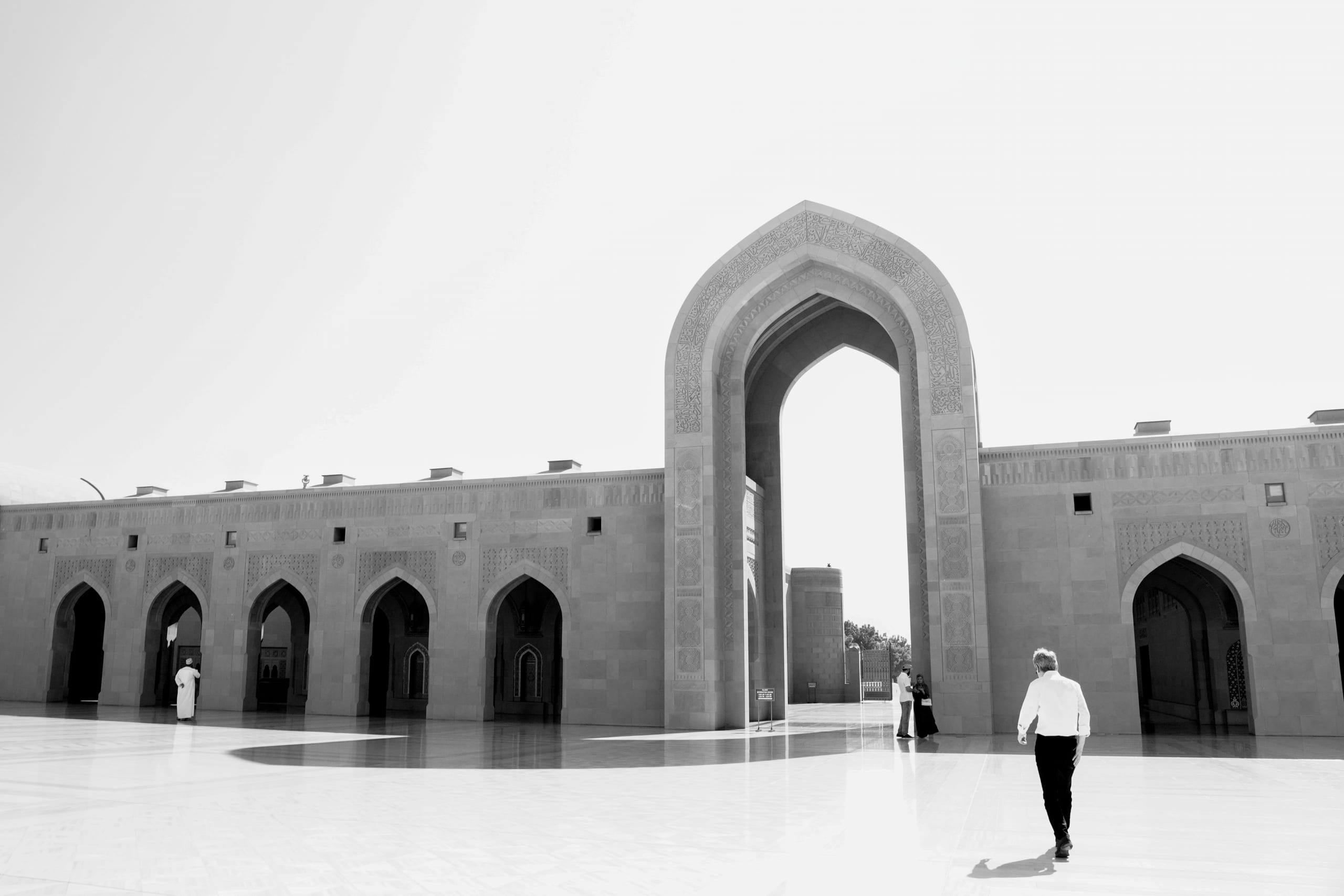 A man infront of Sultan Qaboos mosque entrance, in black and white
