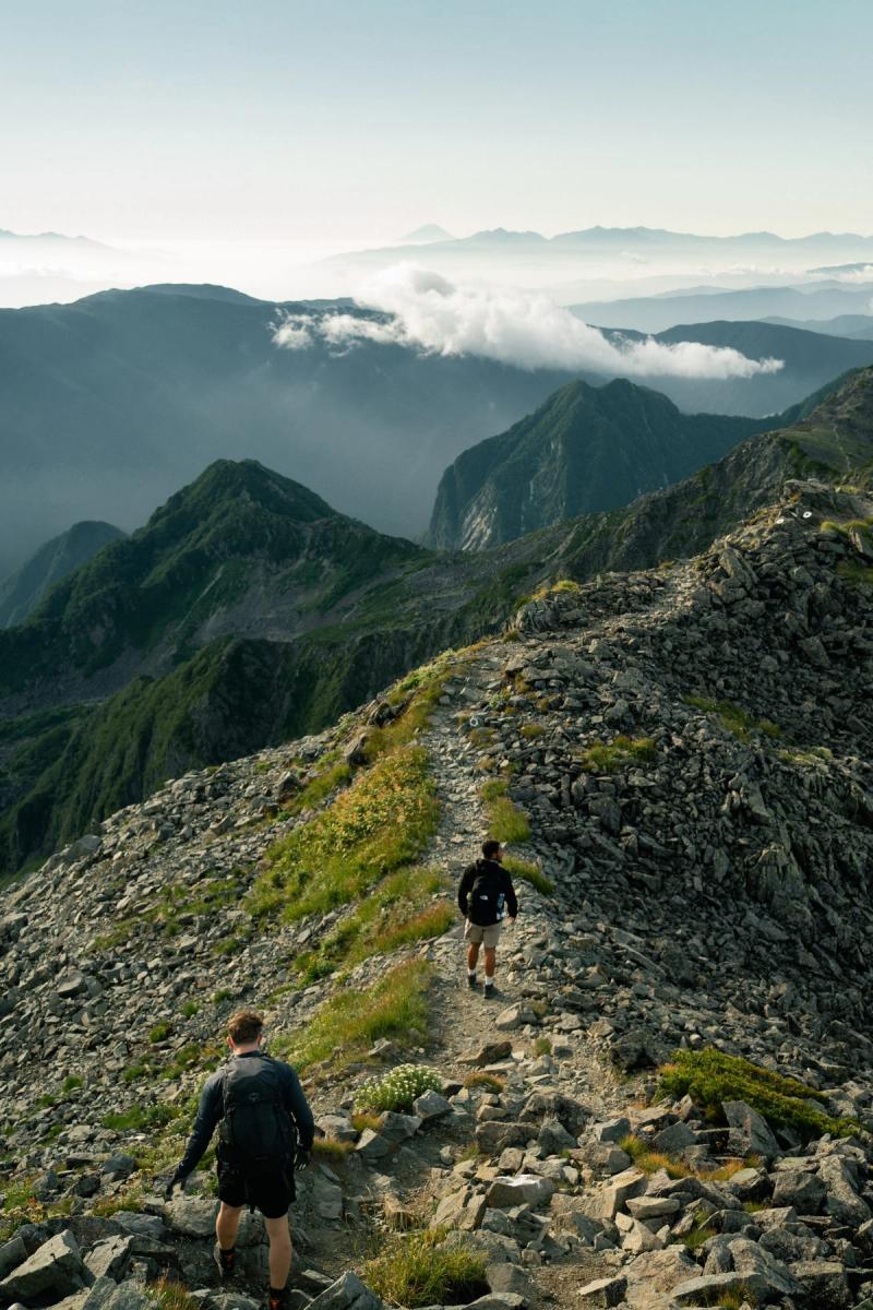 Hikers head down a ridgeline with Fuji in the distance