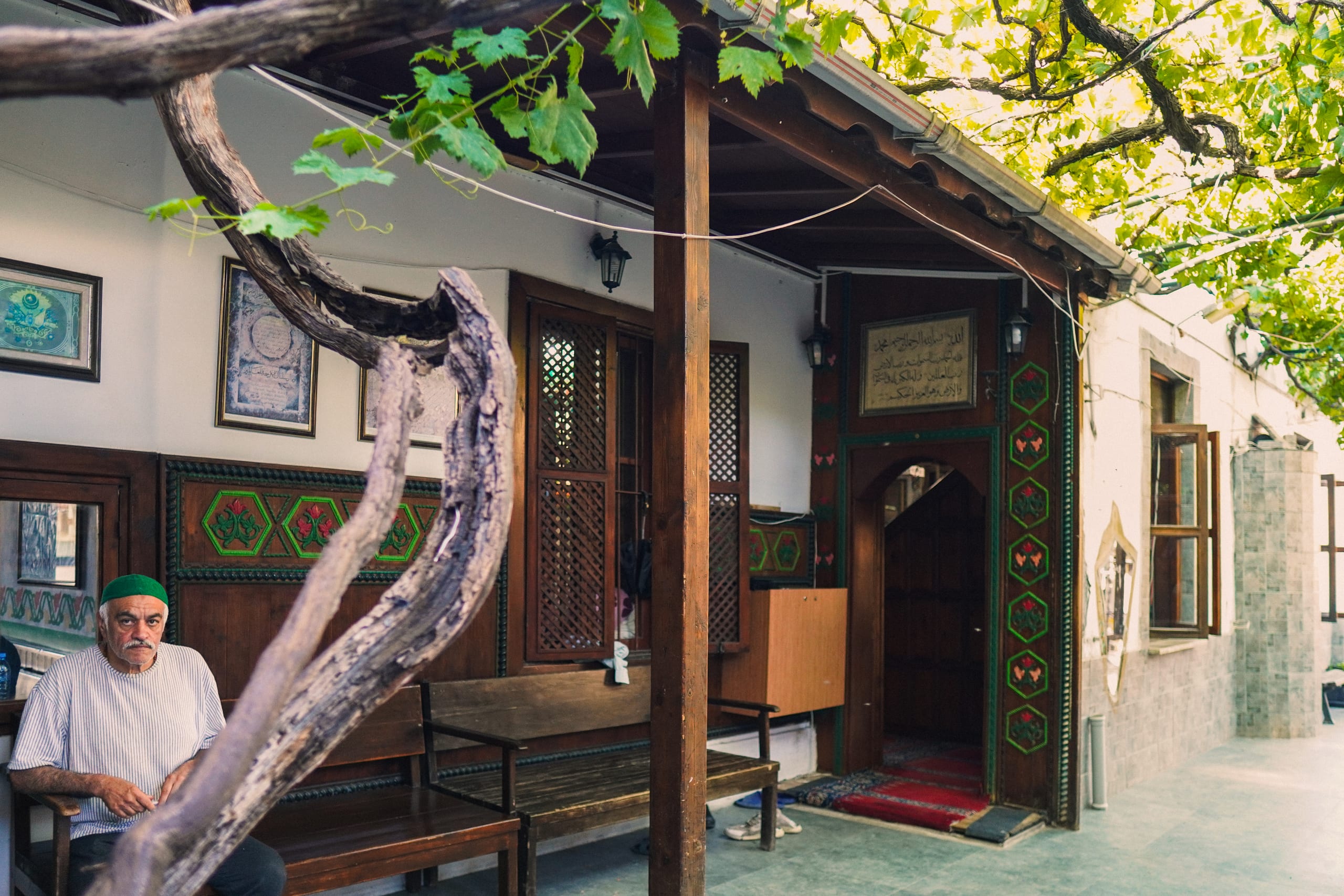 A man sat, tasbih in hand, outside the mosque of the Dergah