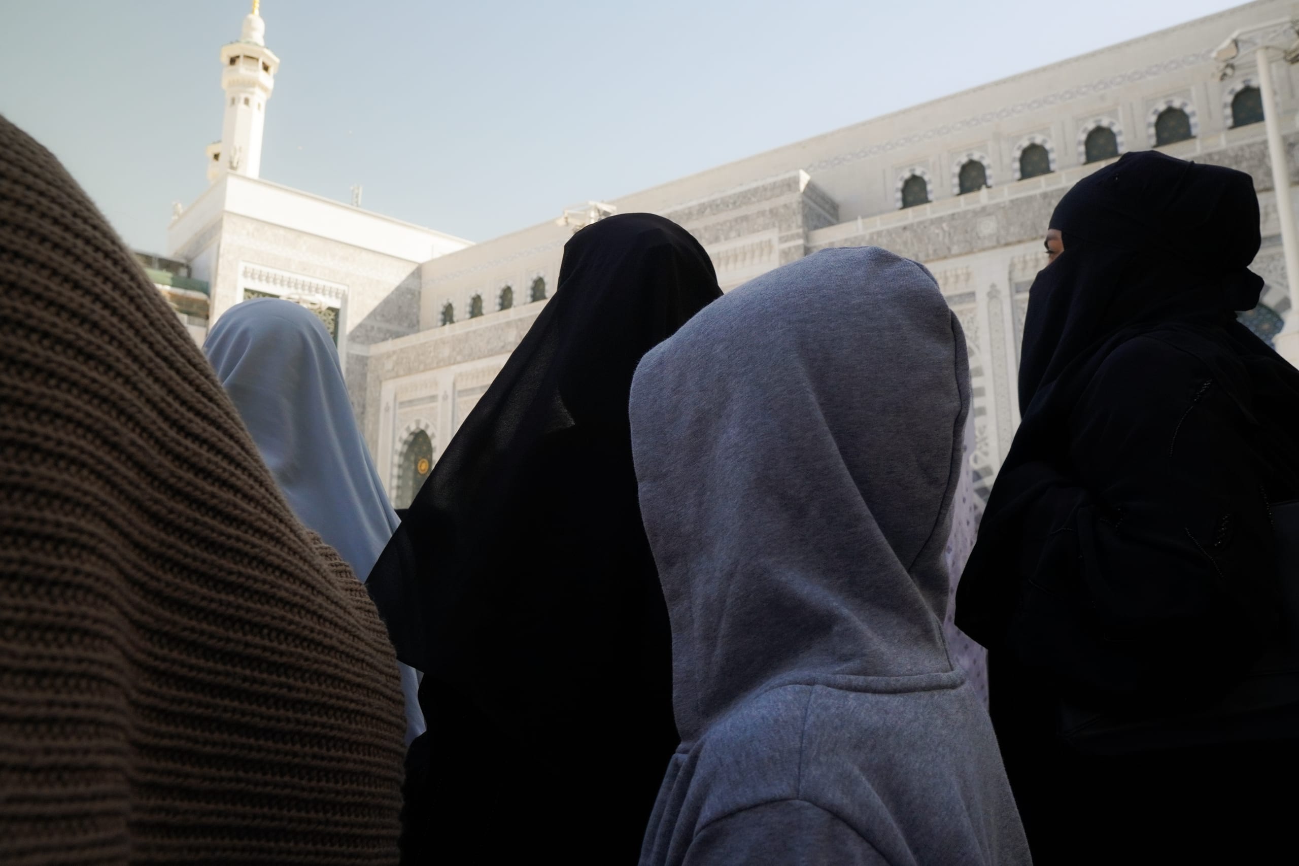Hooded figures crowded outside Masjid al-Haram