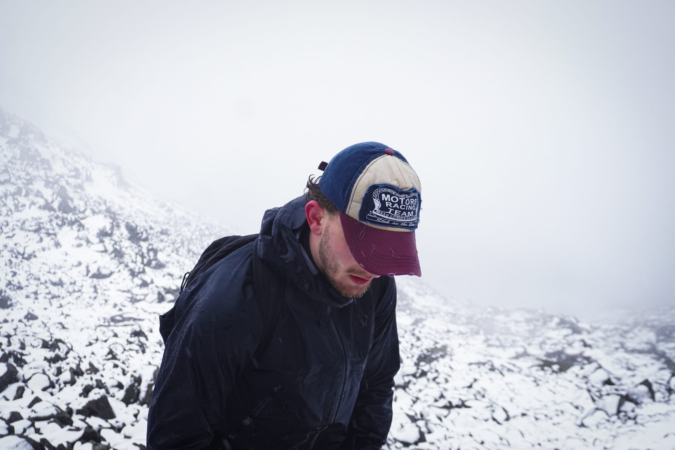 Hiker with a cap surrounded by snowy mountains