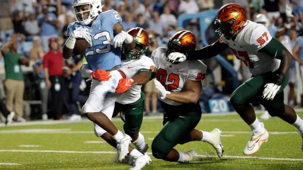 North Carolina's George Pettaway (23) evades Florida A&M's Eric Smith (8), Gentle Hunt (92) and Justin Cooks (57) en route to a touchdown during the second half of an NCAA college football game in Chapel Hill, N.C., Saturday, Aug. 27, 2022.