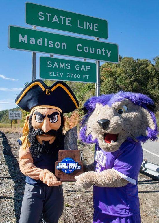 Bucky (ETSU mascot left) and Paws (WCU mascot right) pose at the border of Madison County
