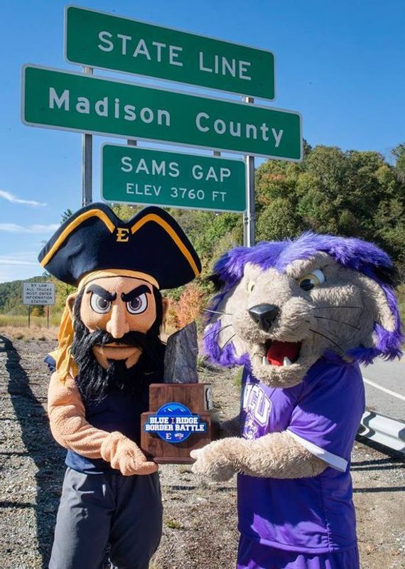 Bucky (ETSU mascot left) and Paws (WCU mascot right) pose at the border of Madison County