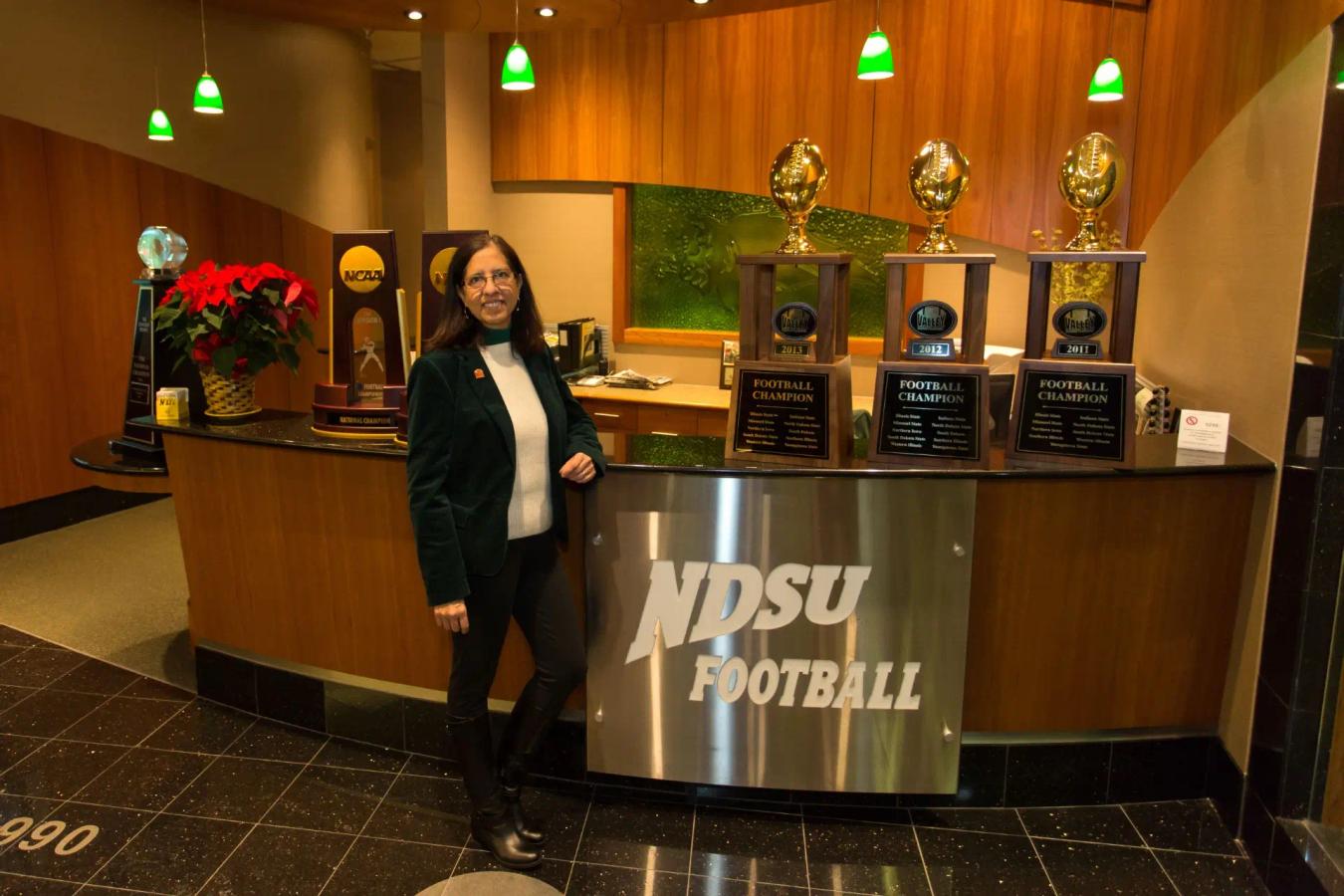 Outgoing MVFC Commissioner Patty Viverto stands in front of NDSU Football trophies