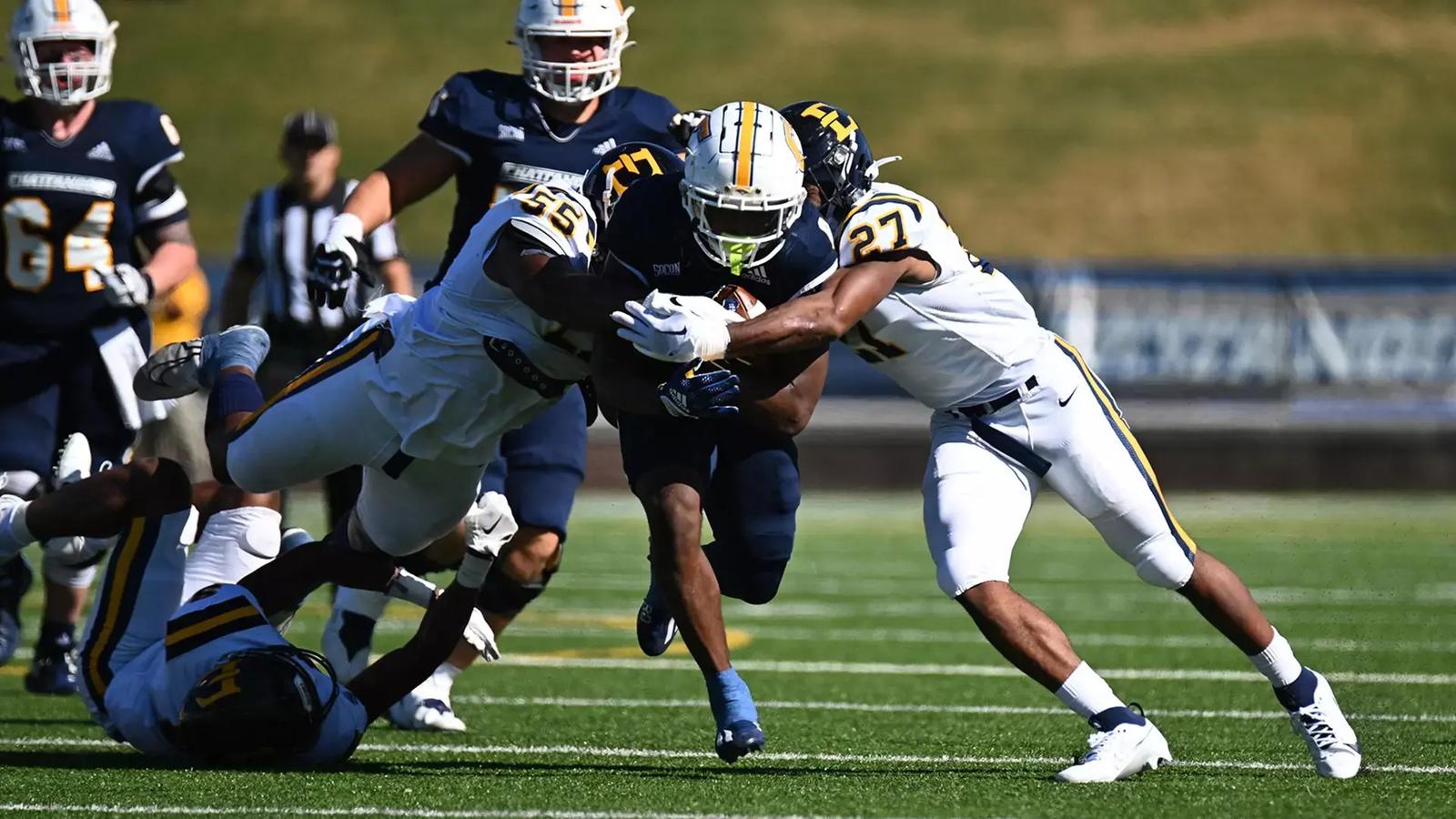 UT-Chattanooga RB Gino Appleberry runs forward as multiple ETSU defenders attempt to take him down.