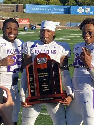Furman football players holding the SoCon Championship trophy