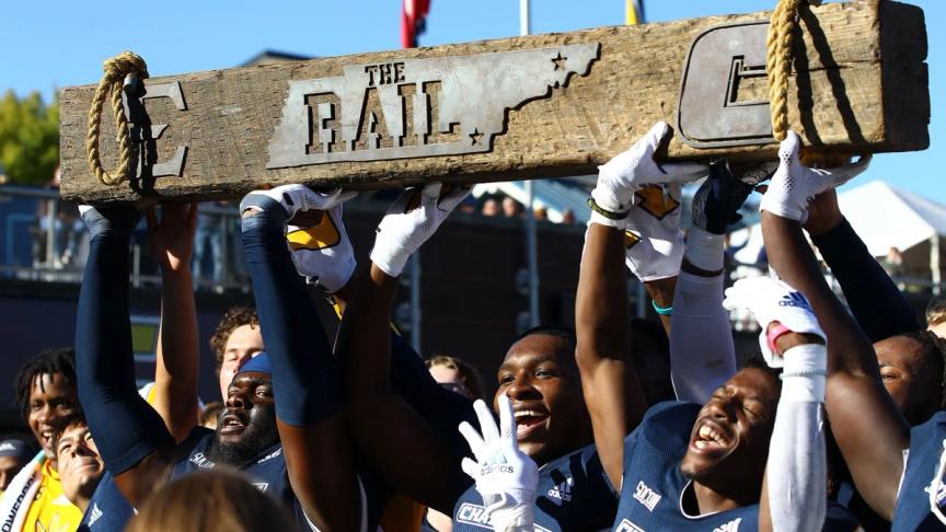 Members of UTC's football team hoist "The Rail" after beating ETSU in the "Rail Rivalry" 21-16 in 2021