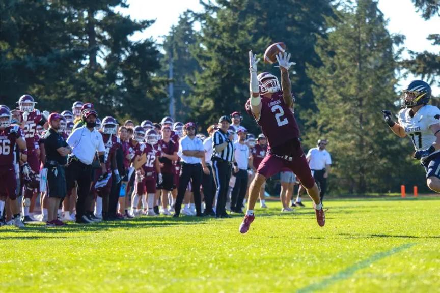 Puget Sound's Izaiah Jerenz reaching up for a catch against George Fox