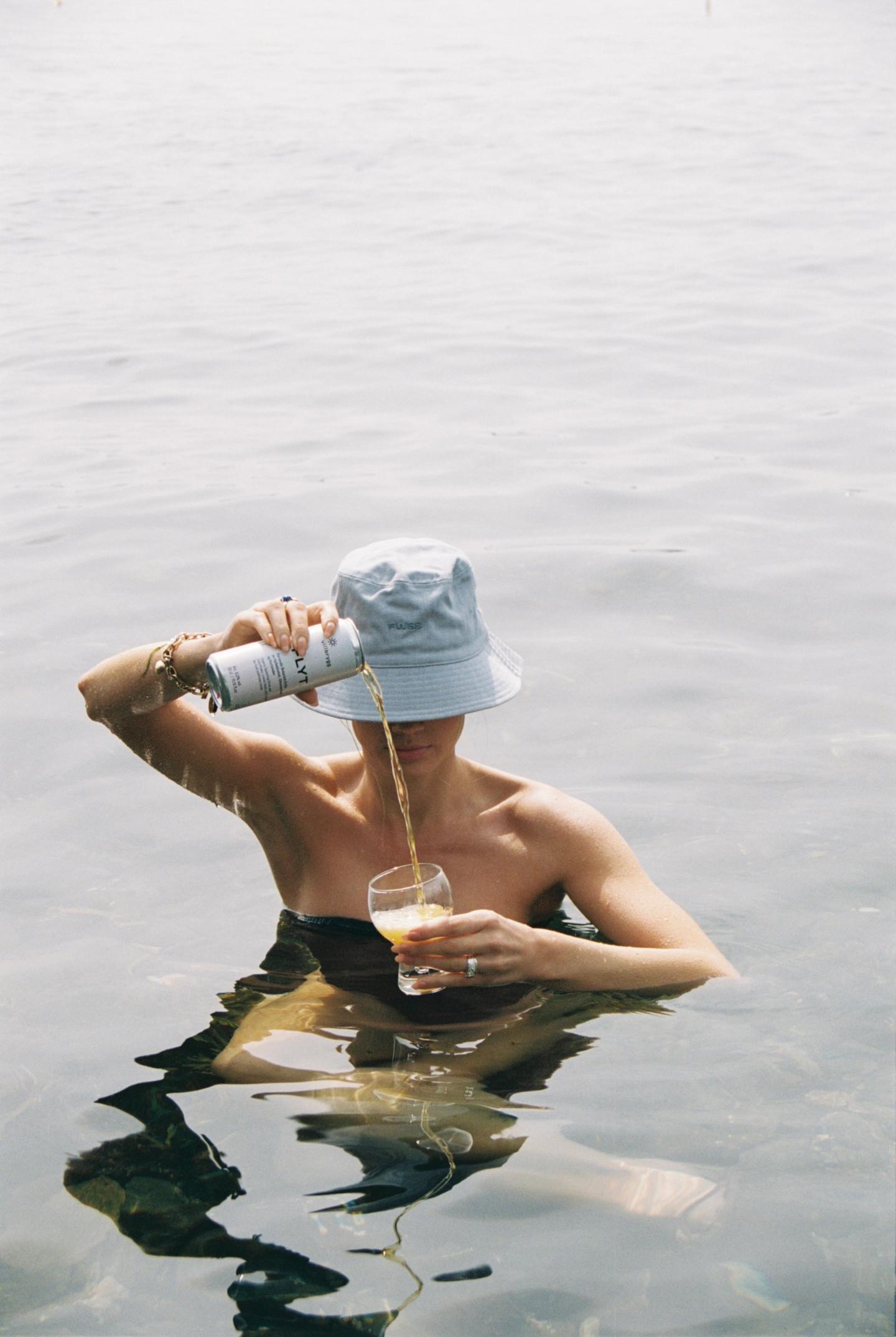 Woman in the water pouring a can of flyt in to a glass