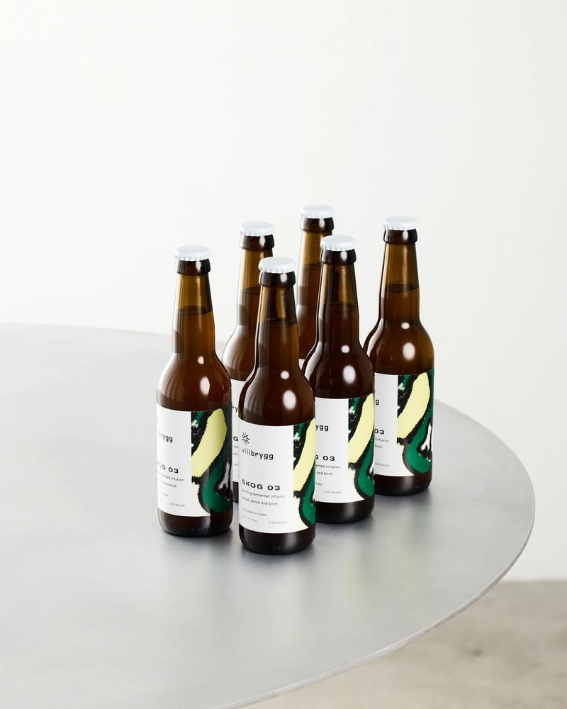 Six bottles of Villbrygg Skog placed on a round metal table – a non-alcoholic, fermented drink inspired by Norwegian nature.