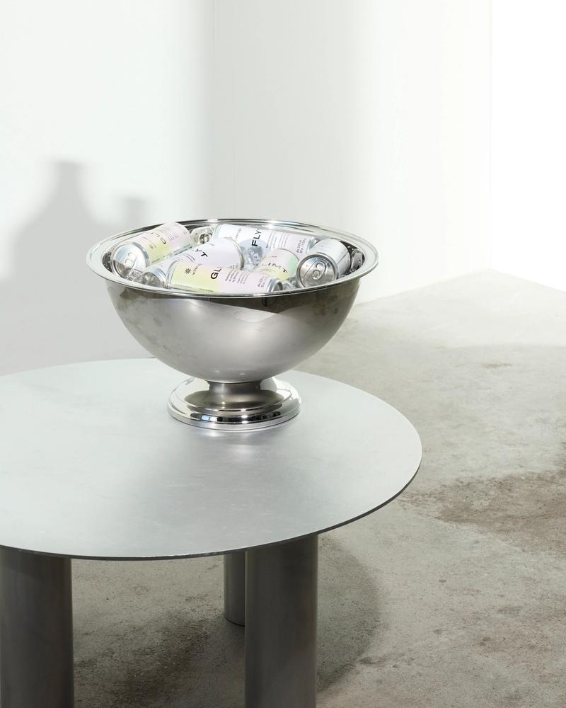 A metal bowl filled with Villbrygg’s alcohol-free cans, placed on a low table in a minimalist room with a concrete floor.