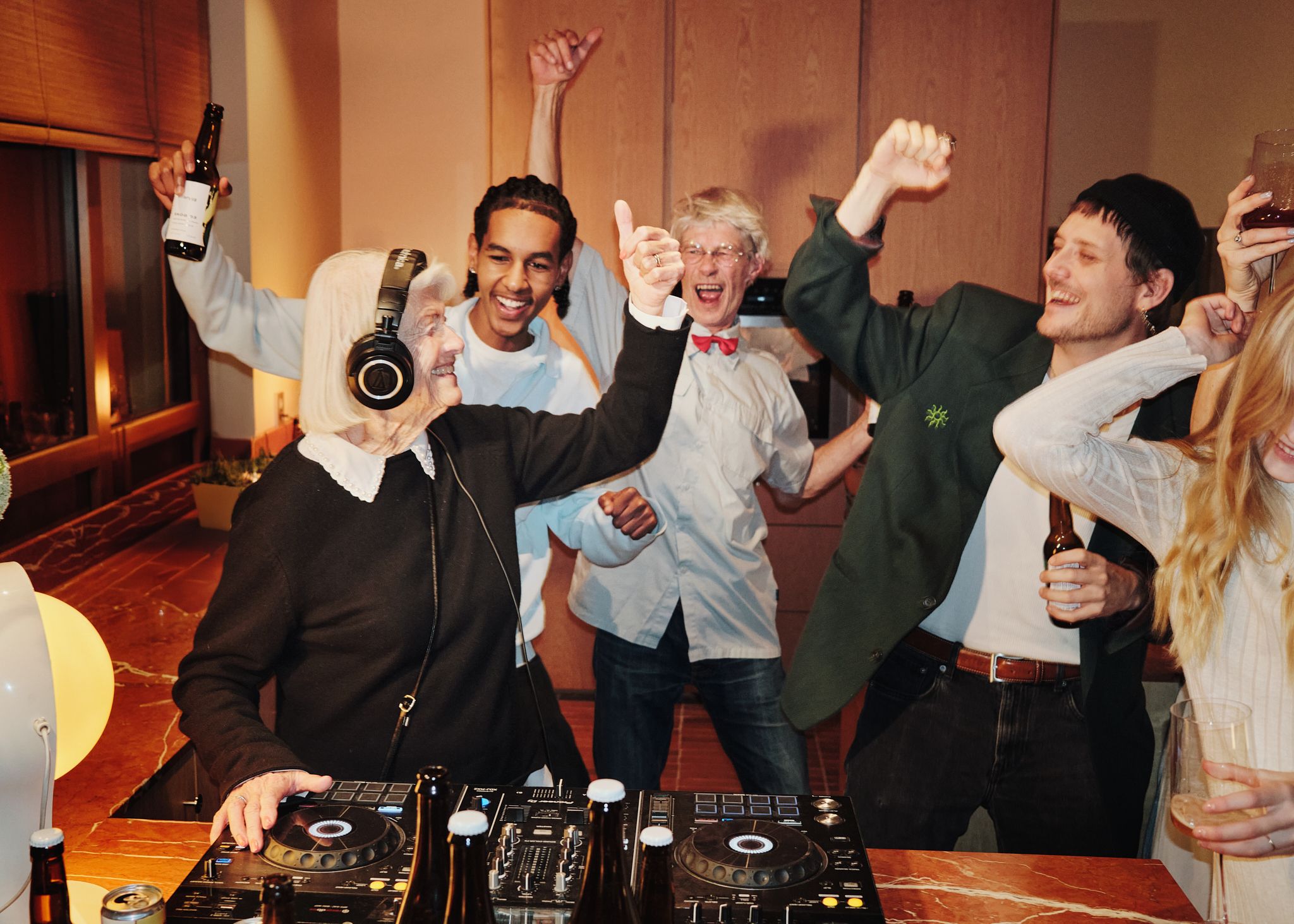 People in all ages partying around a dj table. Old woman djing. 