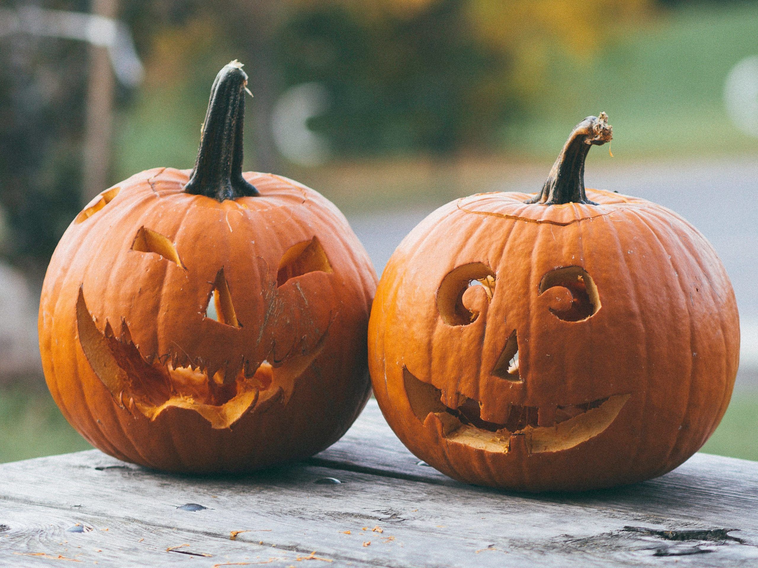 Two carved halloween pumpkins on a wooden table.