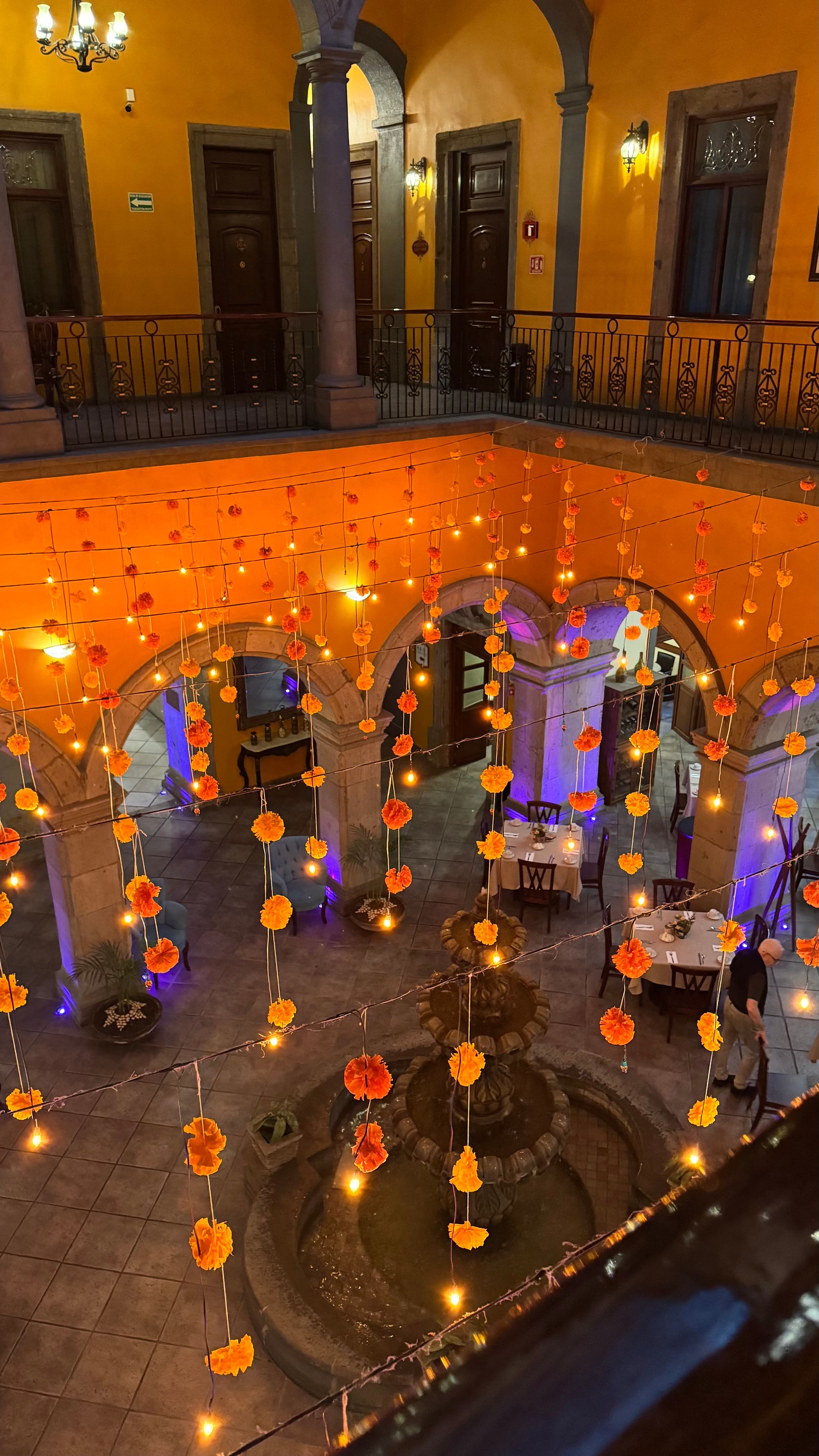 A view into the hotel lobby, with string lights and marigolds hung between the first and second floor
